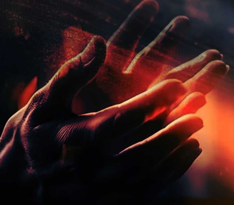 Open hands lifted in prayer, lit in warm orange